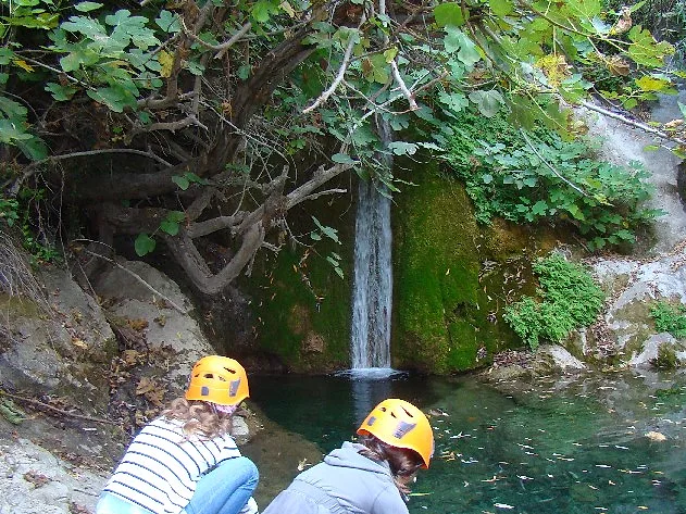 Höhlenwanderer mit Helmen an einem Wasserfall bei Sedella